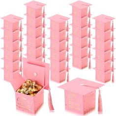 several pink boxes with tassels in them and one has a graduation cap on top