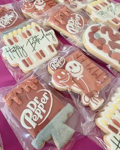 decorated cookies with happy birthday written on them are in plastic bags and placed on a pink tablecloth