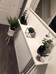 some plants are sitting on top of a white shelf next to a radiator