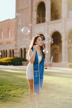 a young woman blowing bubbles in front of a large building with columns and arches on it