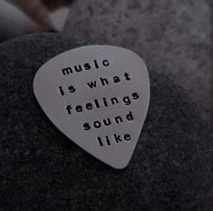 a metal guitar pick with the words music is what feelings sound like written on it