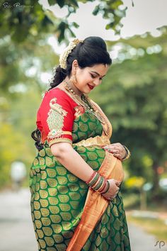 a woman in a green and orange sari is holding her hands on her stomach