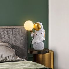 an astronaut lamp on a bedside table next to a bed with green walls and pillows