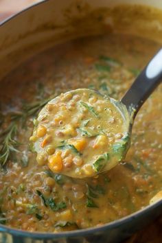 a ladle full of soup being held by a spoon