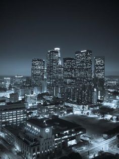 black and white photo of city at night with lights on buildings in the foreground