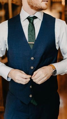 a man wearing a suit and tie with his hands in his pockets