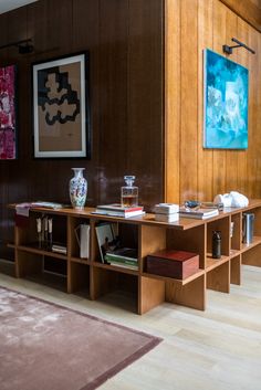 a living room with wooden paneling and art on the wall, including bookshelves