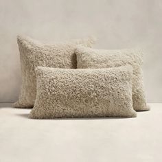 two pillows sitting next to each other on top of a white floor covered in sheep fur