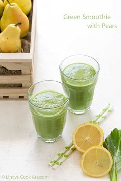 two glasses filled with green smoothie next to sliced lemons