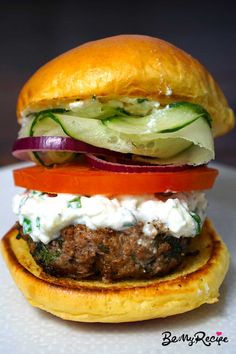 a hamburger with lettuce, tomato and cucumber on it sitting on a plate