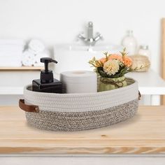 a bathroom sink with soap, toiletries and flowers in it on a wooden table