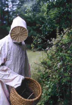 a person in white holding a wicker basket and wearing a protective suit while walking through the woods