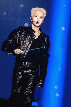 a male in a black leather jacket and some blue lights with a stick on his mouth