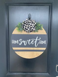 a black door with a wooden sign that says home sweet home on the front and side