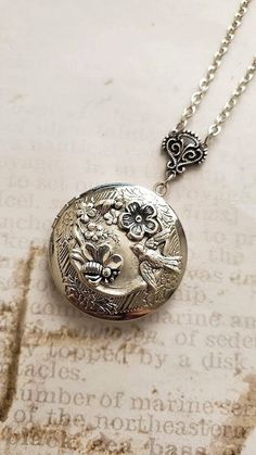 Flower Locket Necklace ~ This silver flower locket is decorated with beautiful flowers and a humming bird design. This can be a great Christmas gift, or a gift for any other occasion. This locket has a nice charming look, and a cozy aesthetic vibe. Chain: ~ Silver Plated Choose YOUR CHAIN LENGTH during checkout ☻More Lockets Here: https://www.etsy.com/shop/FashionCrashJewelry/search?search_query=lockets&order=date_desc&view_type=gallery&ref=shop_search ☻Link to The ENTIRE SHOP: https://www.etsy. Vintage Silver Necklace With Birth Flower, Vintage Silver Necklaces With Birth Flower, Silver Wedding Locket Necklace With Birth Flower, Silver Locket Necklace With Flower Charm As Gift, Vintage Silver Birth Flower Necklace, Elegant Silver Locket Necklace With Flower Charm, Silver Locket Necklace With Birth Flower Round Pendant, Silver Elegant Locket Necklace With Flower Charm, Ornate Silver Locket Necklace As Gift