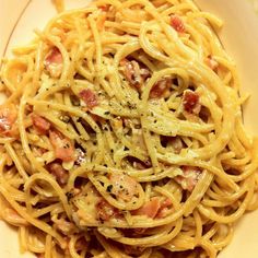 a white plate topped with pasta covered in bacon