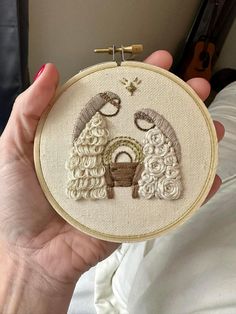 someone is holding up a small embroidery project