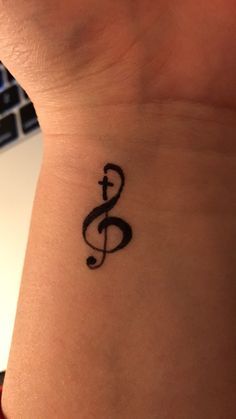 a tattoo on the wrist of a woman with a musical note tattooed on her arm