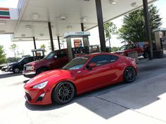 a red sports car parked in front of a gas station