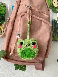 a pink backpack with a green frog face on it's side hanging from a hook