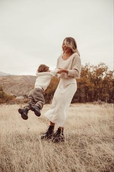 a mother and her son playing in the tall grass with their feet on each other