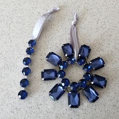 a necklace with blue glass beads and a white ribbon on the floor next to it