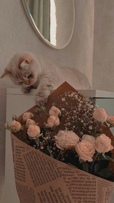 a cat laying on top of a piece of paper with flowers in front of it