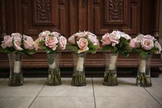 four vases filled with pink roses sitting on the floor