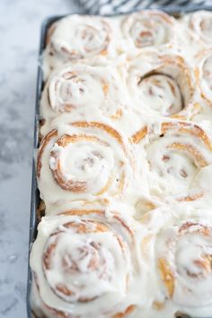 a pan filled with cinnamon rolls covered in icing