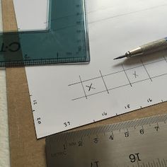 a pen and ruler sitting on top of a piece of paper next to a ruler