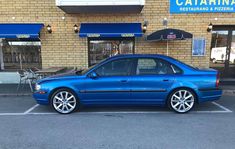 a blue car parked in front of a restaurant