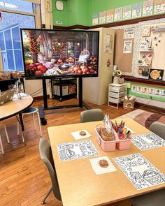 a classroom with desks, chairs and a television in the corner that has pictures on it