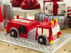 a cake shaped like a firetruck on a table with red and white decorations