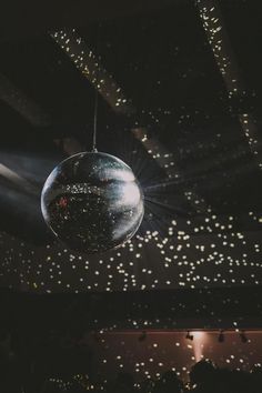 a disco ball hanging from the ceiling in a dark room filled with lights and confetti