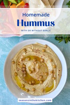 hummus with chickpeas and olives in a white bowl on a blue table