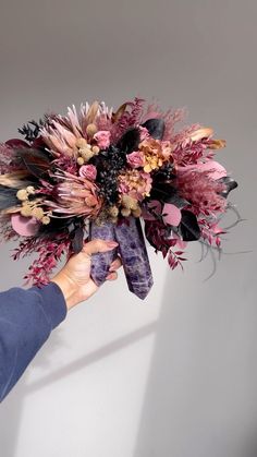 a woman holding a bouquet of flowers in her hand with purple and gold accents on it