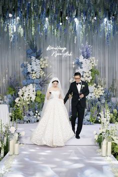 a bride and groom are walking down the aisle at their wedding ceremony in front of an elaborate floral backdrop