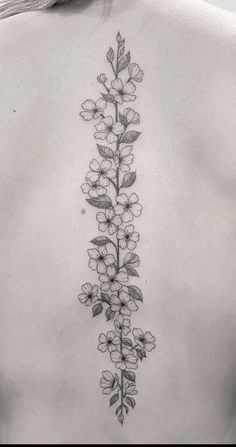 the back of a woman's upper body with flowers and leaves tattooed on it