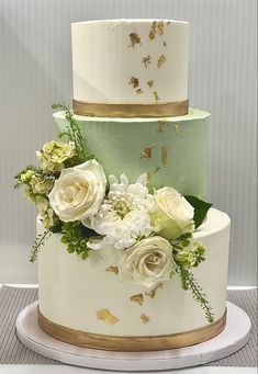 a three tiered cake with white and green flowers