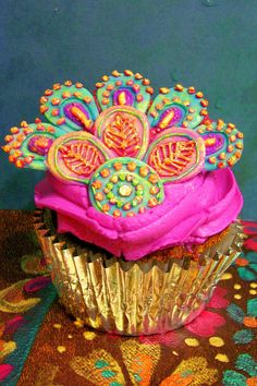 there is a cupcake with pink frosting and decorations on top of the cupcake