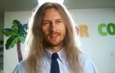 a man with long hair wearing a blue tie