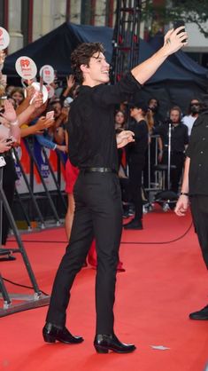 a man standing on top of a red carpet next to a crowd