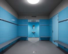 an empty room with blue tile walls and benches