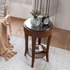 a small table with a clock on it next to a chair and a window in the background