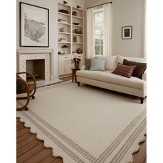 a living room filled with furniture and a white rug on top of a hard wood floor