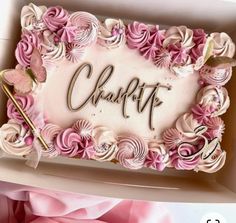 there is a cake in the box decorated with pink flowers and writing that says charlotte