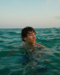 a young man swimming in the ocean with his head above the water's surface