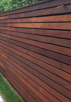 the side of a wooden fence with grass and trees in the background