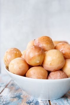 a white bowl filled with donuts on top of a wooden table