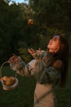 a woman is throwing apples in the air while wearing a dress and holding a basket